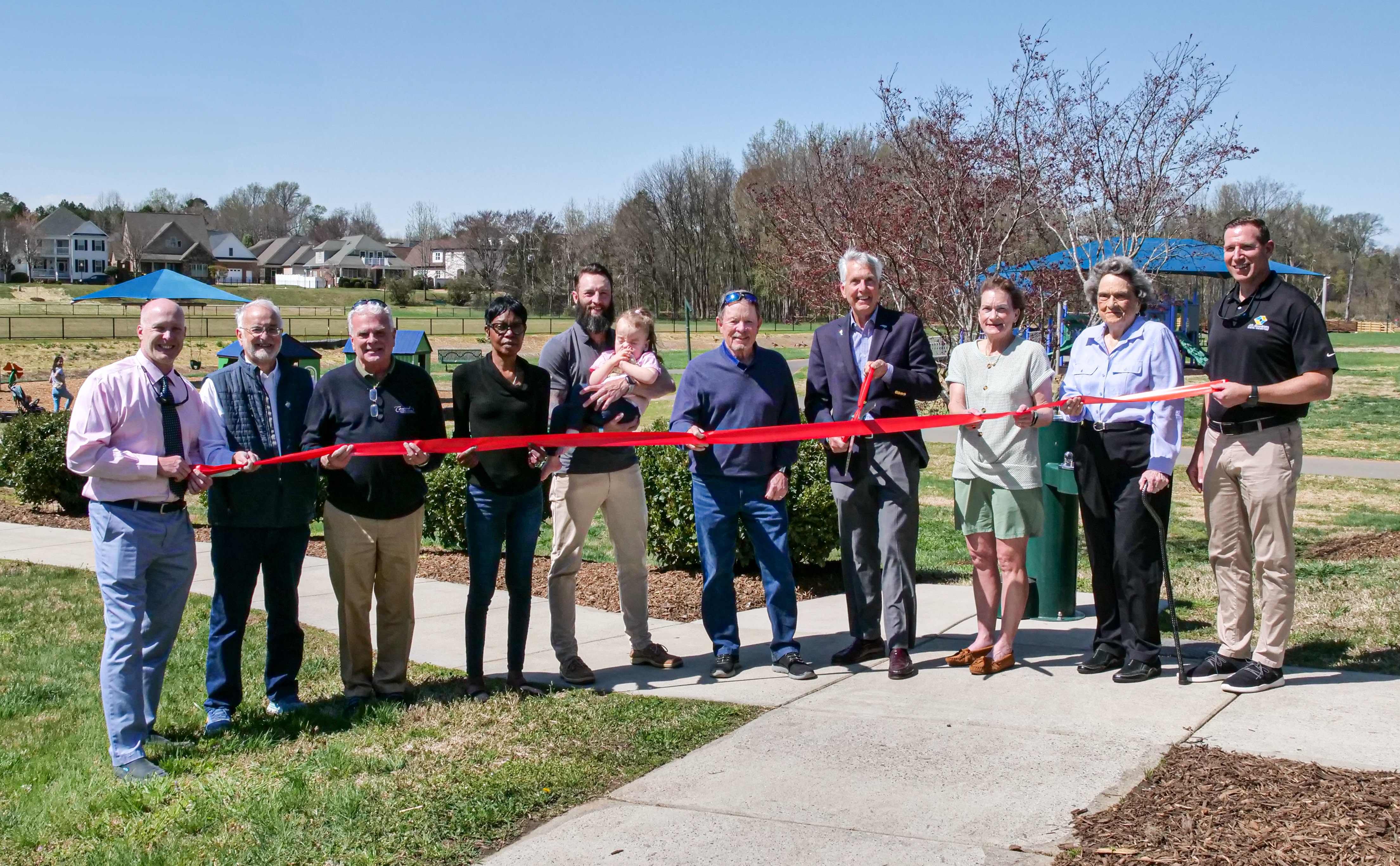 Mayor, City Council, and special guests at the Dorton Park ribbon cutting holding the ribbon.